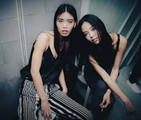 two asian women posing for a photo backstage at fashion week