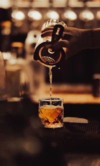 a person pouring a drink into a glass
