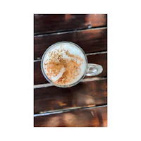 a latte with cinnamon on top of a wooden table