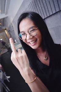 a woman wearing glasses is making a hand gesture