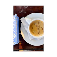 a cup of coffee on a plate next to a book