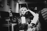 a black and white photo of a woman holding a beer