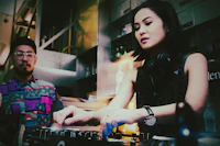 a woman and a man djing in a bar