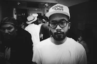 a black and white photo of a man wearing glasses and a hat
