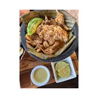 a bowl of pulled pork with a lime and avocado on a tray